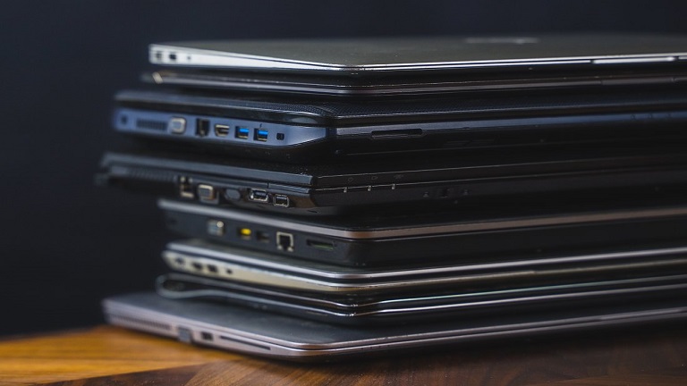 Stack of old laptops with dark background
